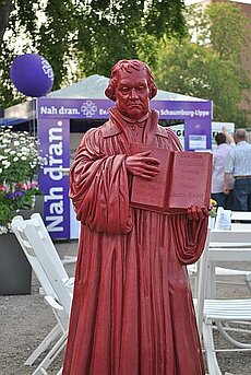 Luther-Zwerg vor einem Informationsstand der Landeskirche